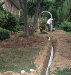 a Plano Sprinkler repair tech lays a new underground supply line
