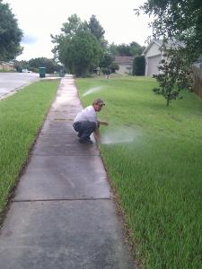 Sprinkler repair technician adjusts a pop up
